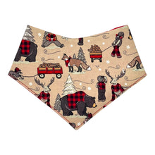 Load image into Gallery viewer, A baby bandana bib with a fabric winter plaid pattern featuring bears, beavers, deer, and foxes in a snowy setting.
