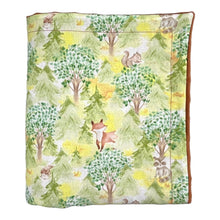 Load image into Gallery viewer, Baby blanket by Mimi’s Little Loveys. Features cute foxes, raccoons, squirrels in a forest scene. Shades of browns, oranges, grays, and greens, on a yellow background. Backing is a brown minky.
