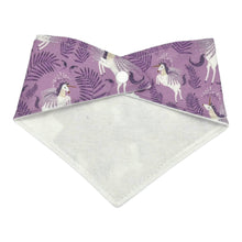 Load image into Gallery viewer, Baby bandana bib by Mimi's Little Loveys. White unicorns on a purple background. Leaf and flower details. White backing shown with single snap.