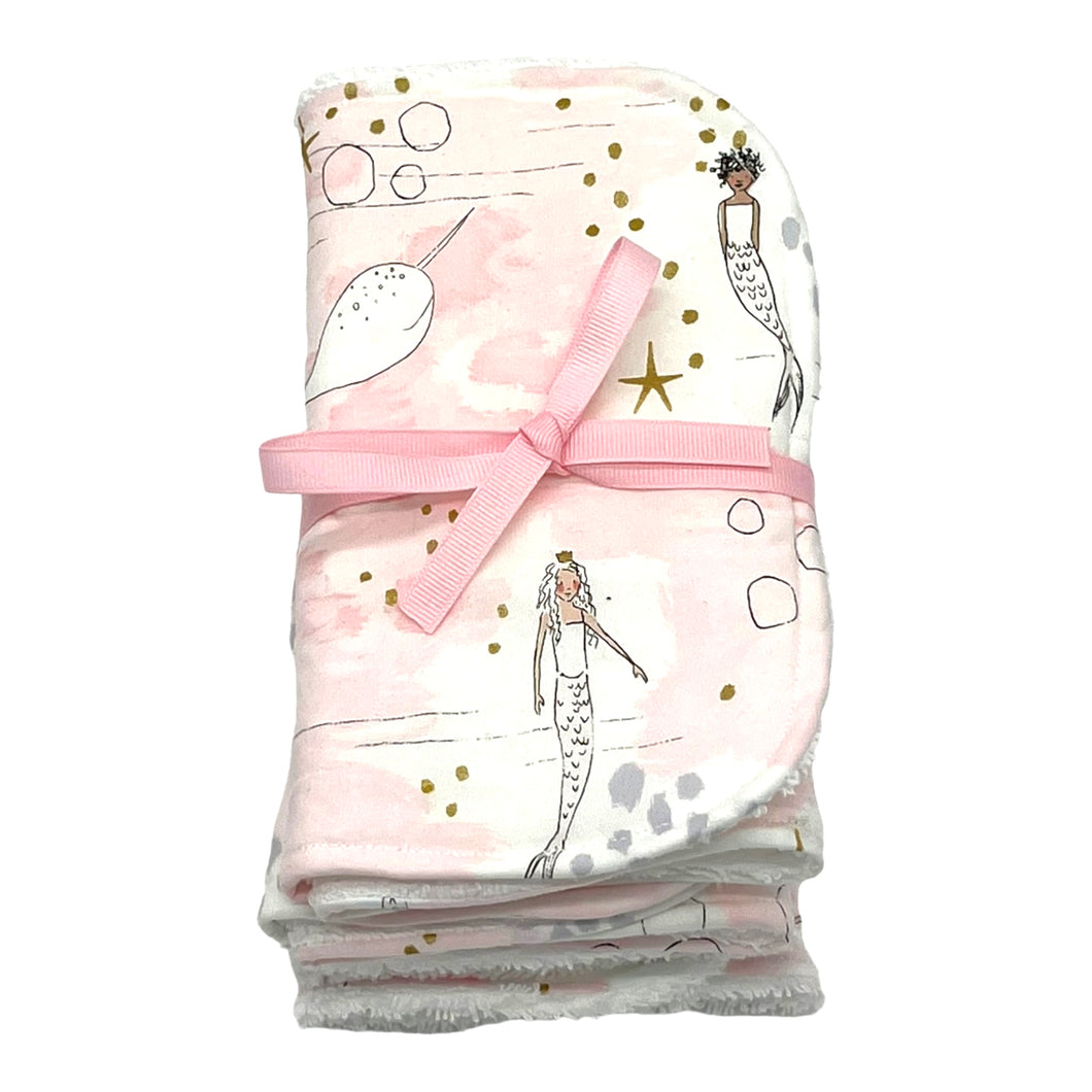 Burpcloth set by Mimi's Little Loveys. Whimsical mermaids & narwhals on a light pink background with metallic gold accents.