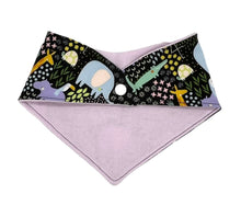 Load image into Gallery viewer, Baby bandana bib by Mimi&#39;s Little Loveys. Fun and vibrant design, featuring crocodiles, elephants, flamingos, giraffes, hippos, tortoises, plants, and flowers, on a black background. Backing is soft flannel.
