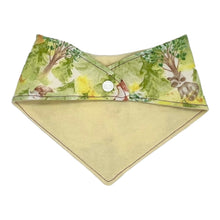 Load image into Gallery viewer, Baby bandana bib by Mimi's Little Loveys. Features cute foxes, raccoons, squirrels in a forest scene. Shades of browns, oranges, grays, and greens, on a yellow background. Backing is a cream flannel.
