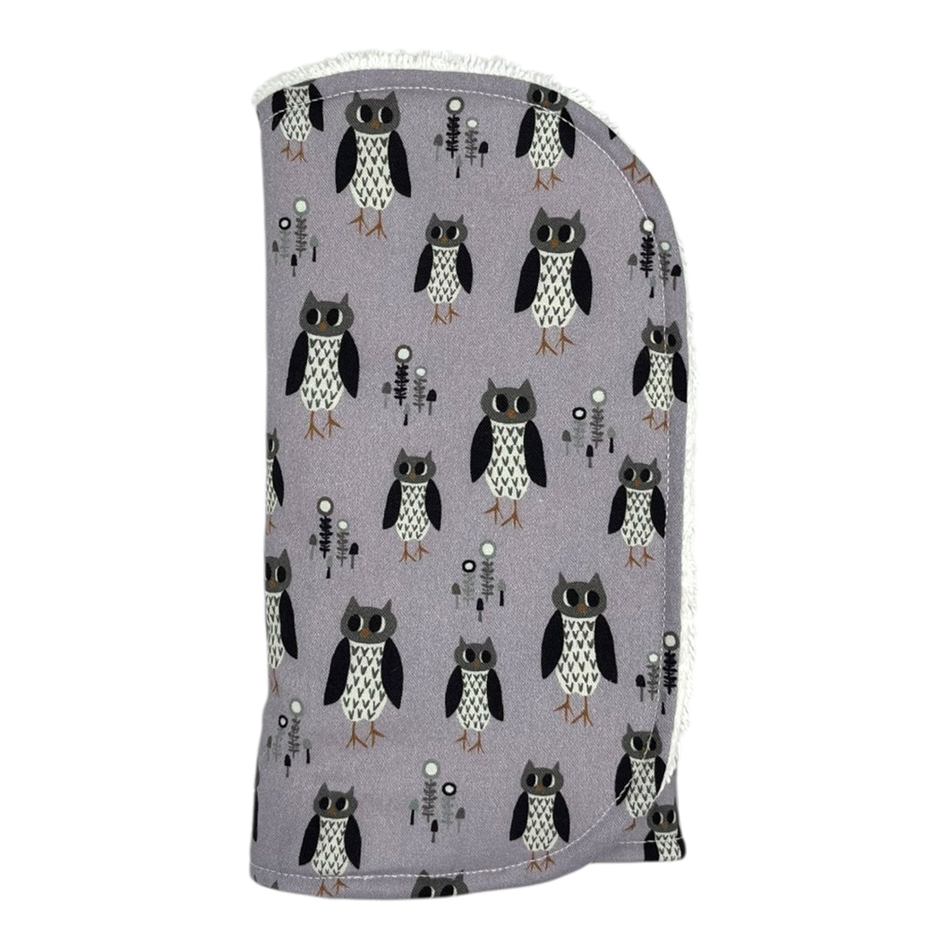Burpcloth with owl pattern on a light purple background.