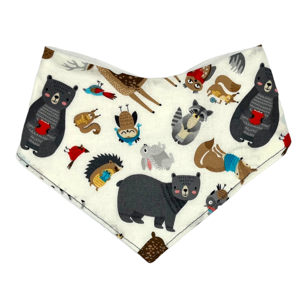 Baby bandana bib by Mimi's Little Loveys. Front features a collection of Maine critters: bears, cardinals, deer, moose, owls, porcupines, raccoons, squirrels, all on a white background. Backing is soft, white, flannel.