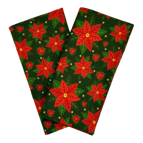 A pair of cotton napkins with red poinsettias on a green background. 