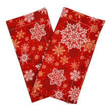 Load image into Gallery viewer, A set of two red dinner napkins with a white, gold, and red snowflake pattern.
