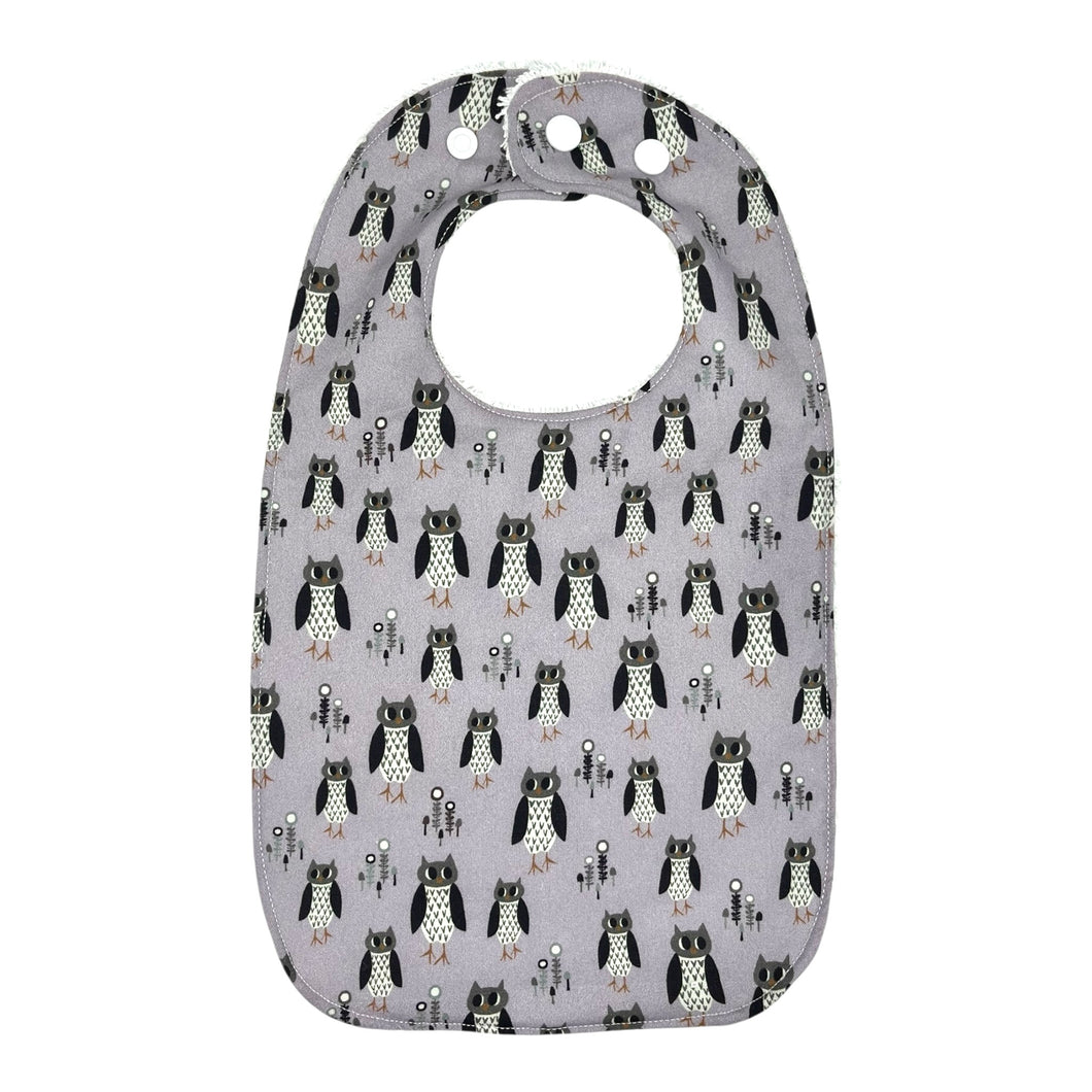 Baby bib with owl pattern on a light purple background.