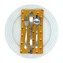 Load image into Gallery viewer, Mustard yellow napkin with red floral pattern on a white dinner plate with cutlery.
